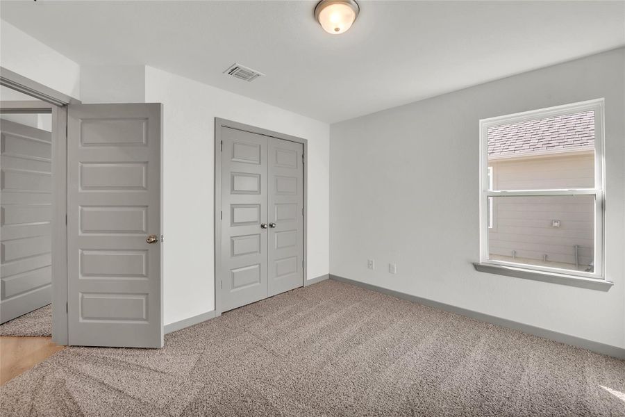 Unfurnished bedroom featuring light carpet and a closet
