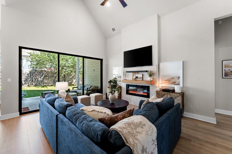 Living area featuring vaulted ceilings, wood-finish flooring, and a fireplace with a light-toned tile surround and wood mantel
