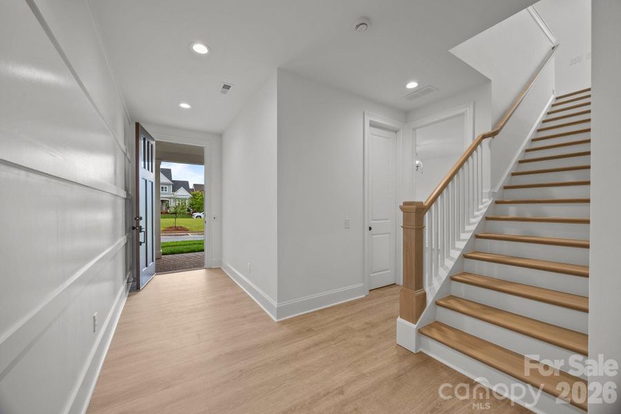 Entry with custom millwork and white oak stairway leading upstairs