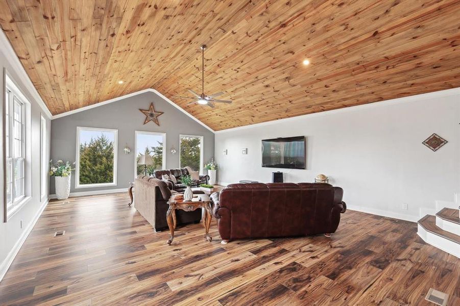 Living room featuring wood ceiling, ceiling fan, wood-type flooring, and vaulted ceiling