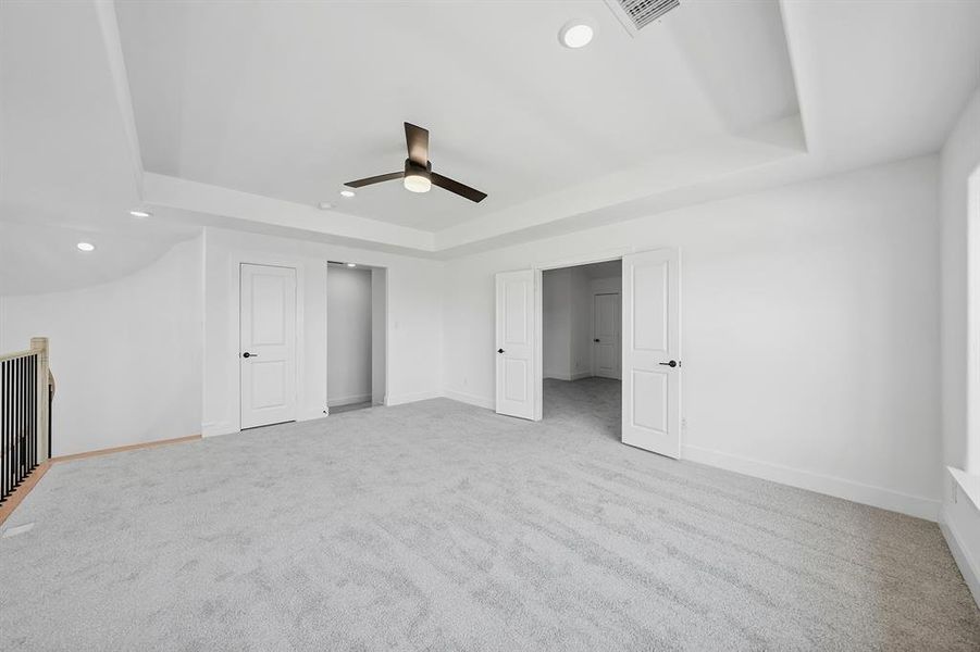 Unfurnished bedroom featuring a raised ceiling, recessed lighting, light colored carpet, and a ceiling fan