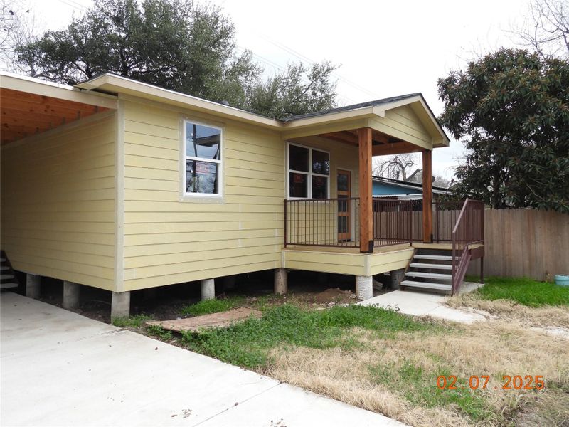 View of side of property with fence, a deck, and a carport