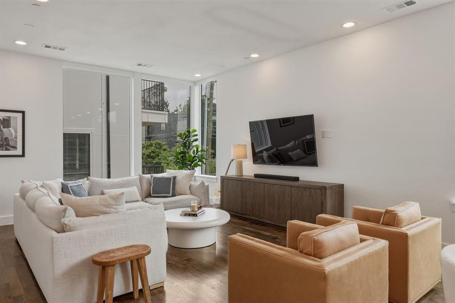 Living area featuring hardwood floors, recessed lighting, and large windows providing natural light