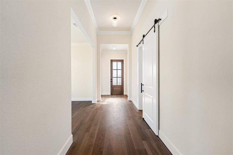Corridor featuring a barn door, dark wood-style flooring, and ornamental molding