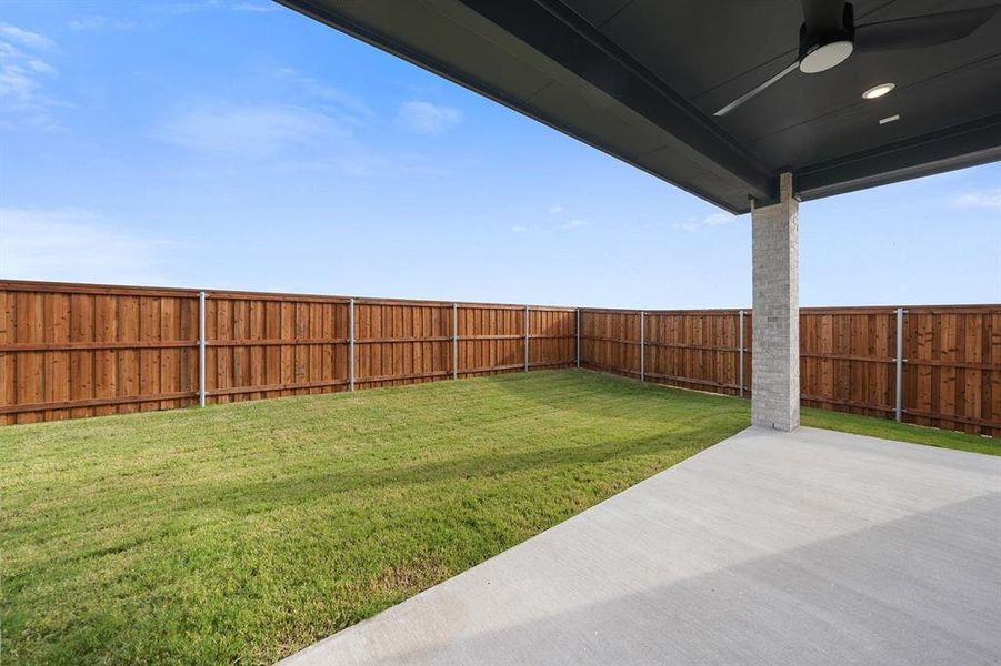Fenced backyard featuring a patio area and a ceiling fan