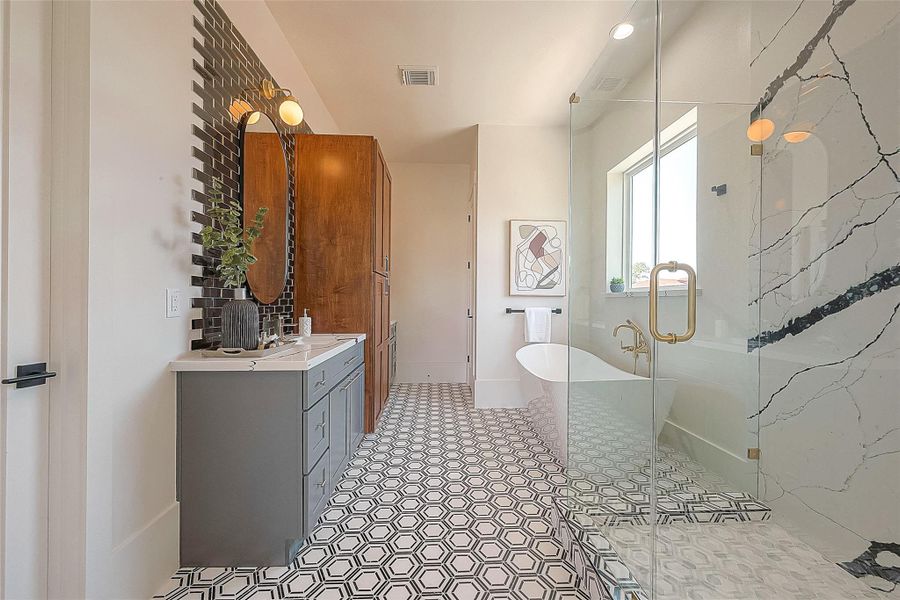 This is a modern bathroom featuring a geometric patterned floor, a sleek standalone bathtub, a glass-enclosed shower with marble walls, a vanity with gray cabinetry and a wooden storage cabinet, accented by gold-toned fixtures and a round mirror. This is a modern bathroom featuring a geometric patterned floor, a sleek standalone bathtub, a glass-enclosed shower with marble walls, a vanity with gray cabinetry and a wooden storage cabinet, accented by gold-toned fixtures and a round mirror.
