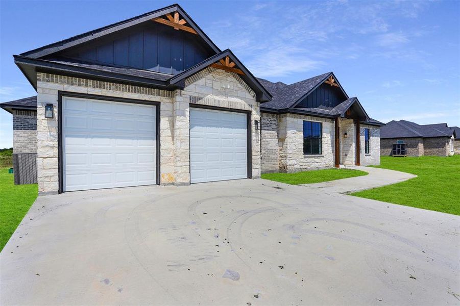 Craftsman inspired home featuring a garage and a front lawn