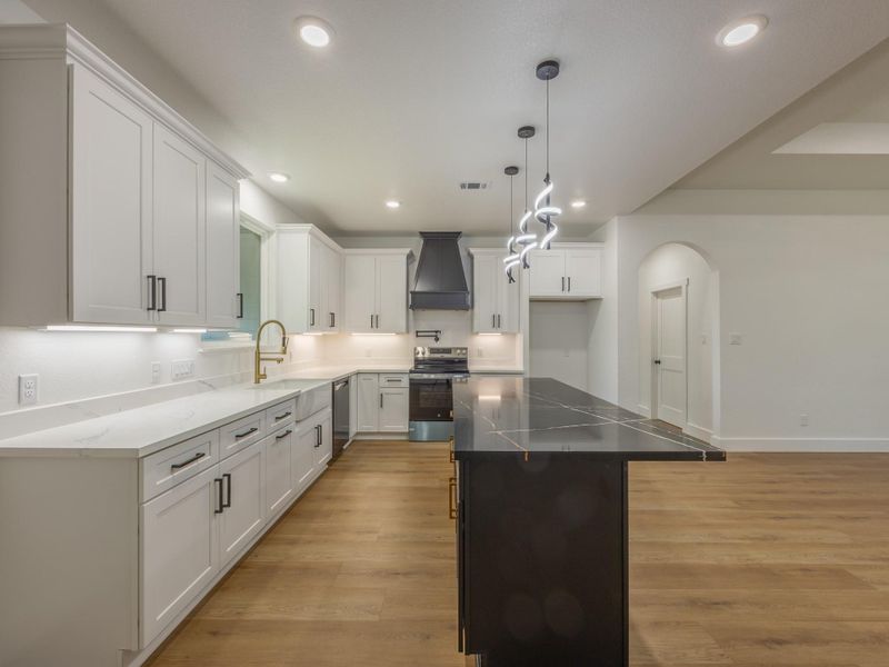 An abundance of cabinetry, deep drawers, and a walk-in pantry (not pictured) ensure this kitchen is as practical as it is beautiful. The black island with gold accents provides extra flair. An abundance of cabinetry, deep drawers, and a walk-in pantry (not pictured) ensure this kitchen is as practical as it is beautiful. The black island with gold accents provides extra flair.