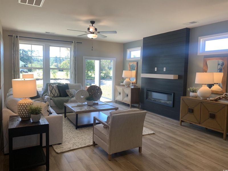 Living room with a fireplace, wood finished floors, and ceiling fan