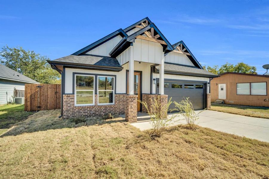 Front view with board and batten siding, brick accents on the home and pillars, wood accents on roof and gutters.