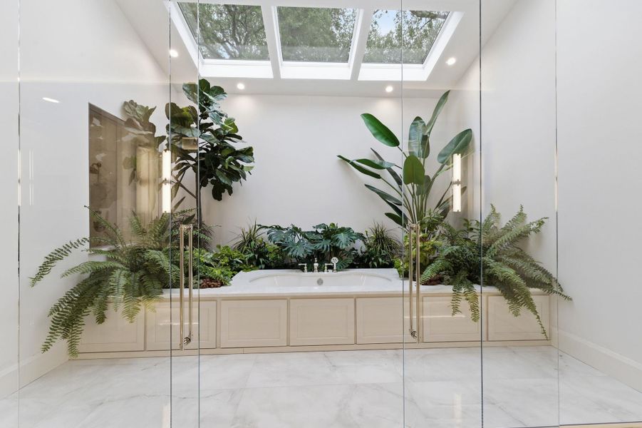 Bathroom featuring a skylight, a bath, recessed lighting, and marble finish floors
