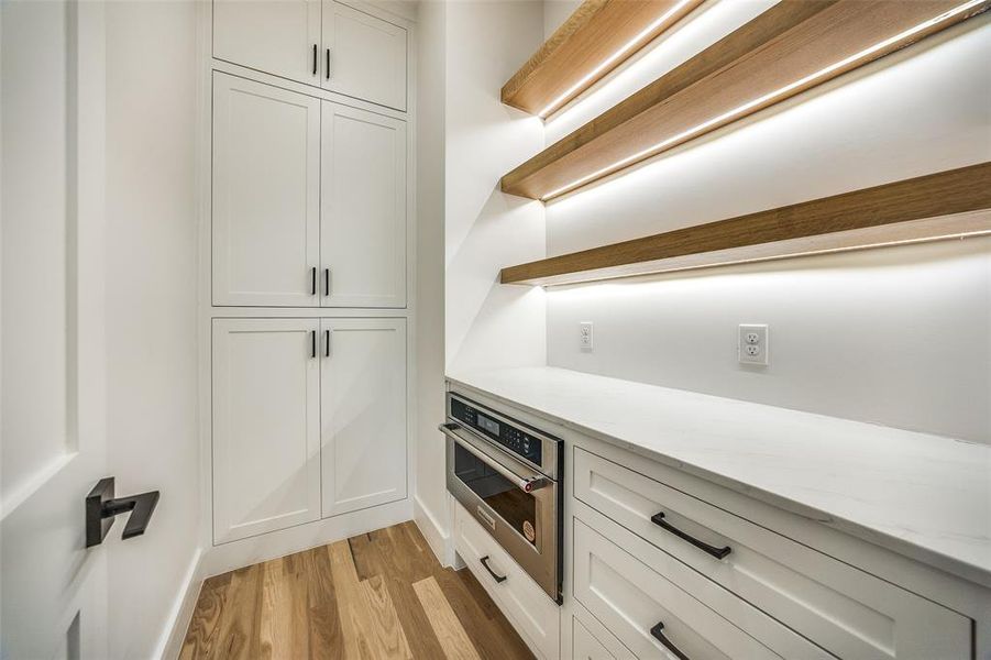 Kitchen featuring white cabinetry, light hardwood / wood-style flooring, oven, and light stone countertops