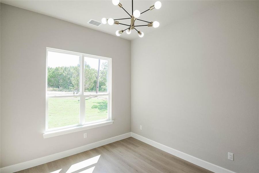 Unfurnished room with a chandelier and light wood-style floors Unfurnished room with a chandelier and light wood-style floors