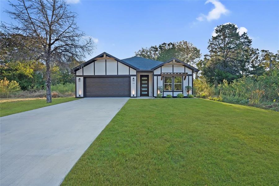 View of front of house featuring a front yard, concrete driveway, a garage, and board and batten siding