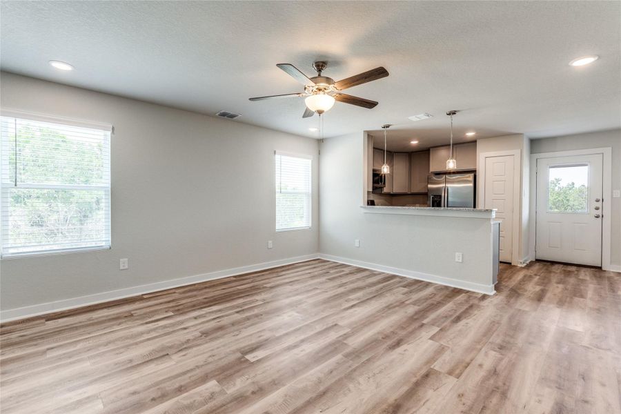 Unfurnished living room featuring recessed lighting, a ceiling fan, light wood-style floors, and a textured ceiling Unfurnished living room featuring recessed lighting, a ceiling fan, light wood-style floors, and a textured ceiling