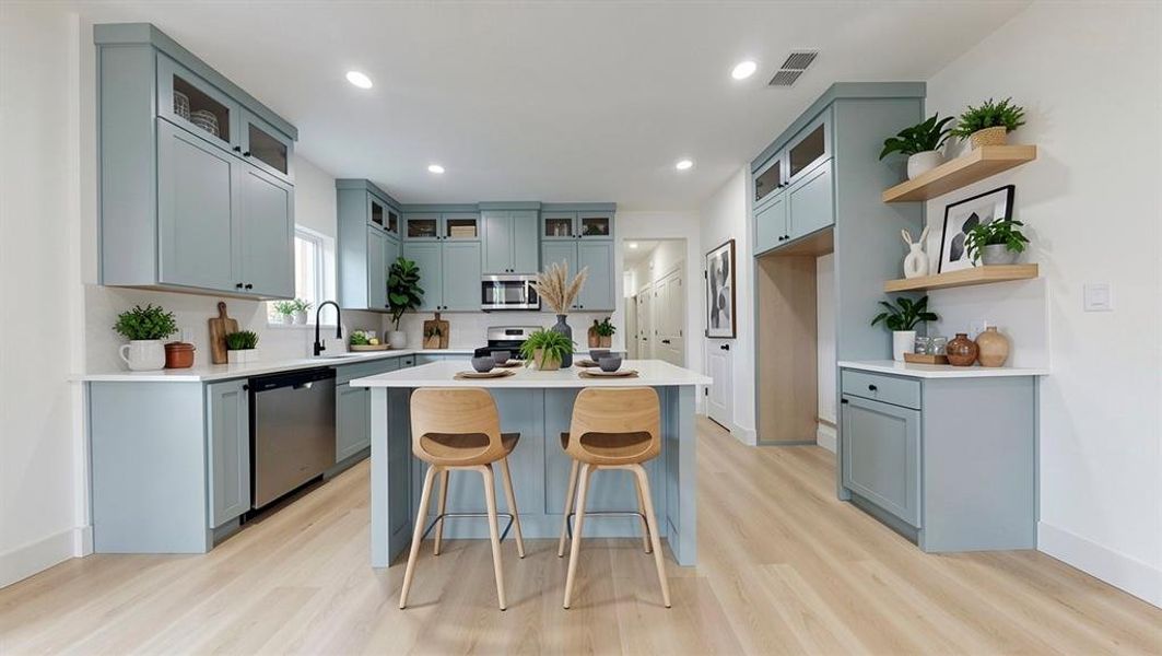 Open-concept kitchen featuring light blue cabinetry, white countertops, and wood-finish flooring