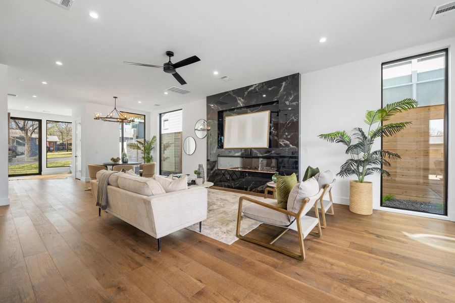 Living room with recessed lighting, visible vents, wood-type flooring, and ceiling fan with notable chandelier