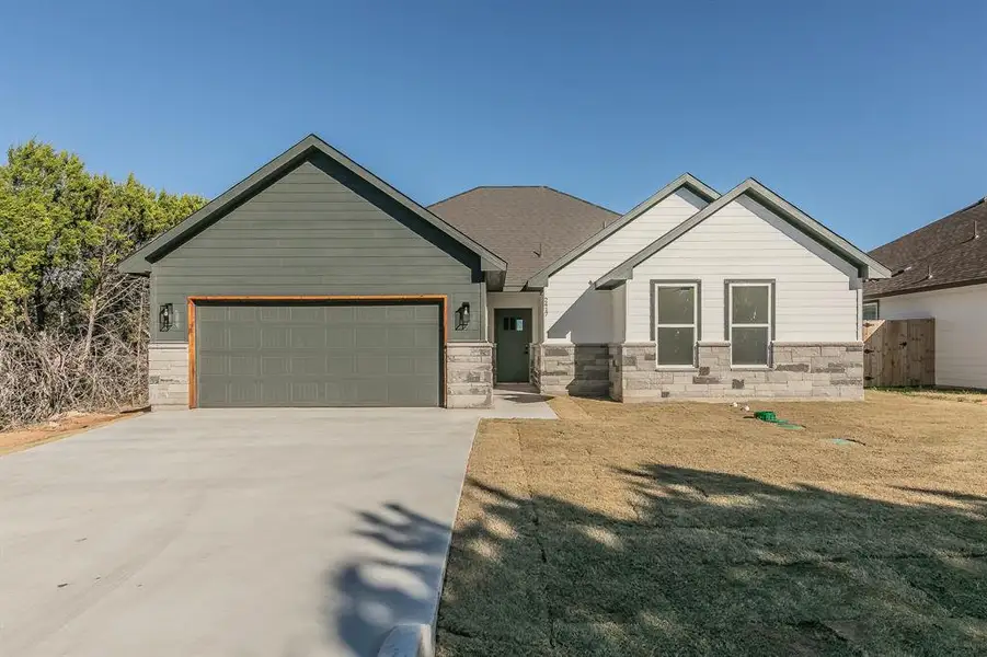 Craftsman inspired home featuring a garage, concrete driveway, and a front yard