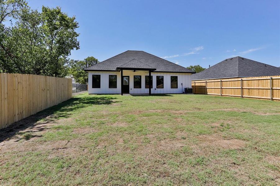 Rear view of property featuring a yard and central air condition unit