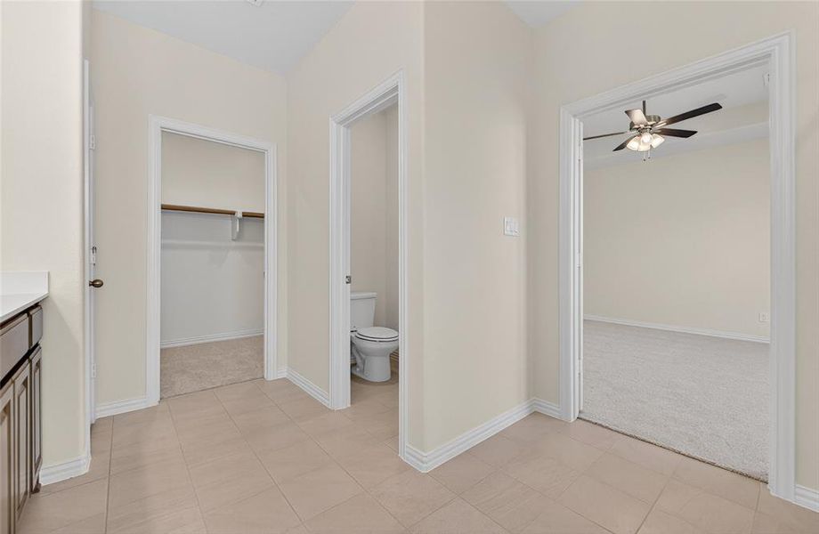 Full bath with a walk in closet, light carpet, vanity, a ceiling fan, and light tile patterned floors