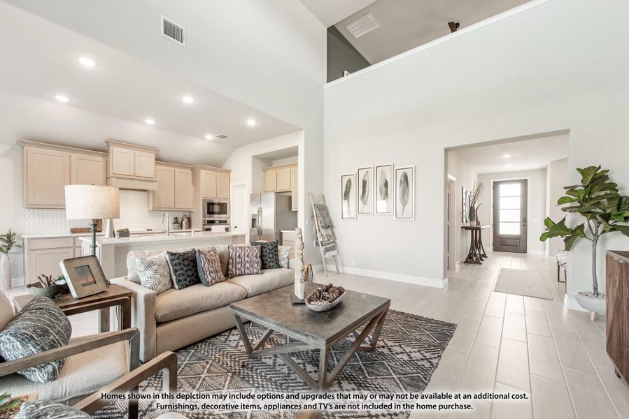 Open-concept living room with high ceilings, tile floors, and kitchen visible in background