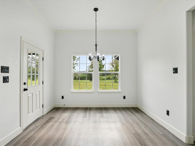 Unfurnished dining area with a notable chandelier, crown molding, and light hardwood / wood-style floors