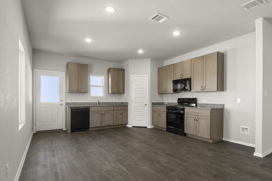 Image of a dining/ kitchen with dark vinyl flooring, light brown cabinets, black appliances and a window above the window