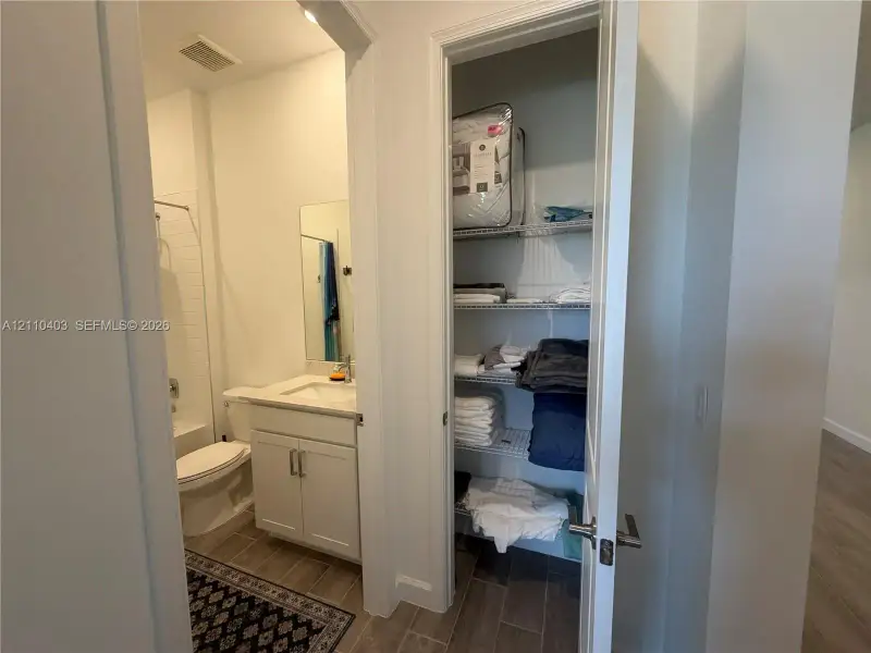 Bathroom featuring a white vanity cabinet, square undermount sink, and tile flooring, with a reach-in closet containing white wire shelving