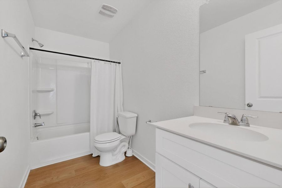 Bathroom featuring vanity, shower / bath combination with curtain, and light wood-style floors