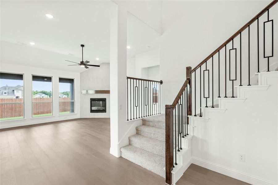 Open living area with hardwood floors, fireplace, and staircase with wood and iron railing Open living area with hardwood floors, fireplace, and staircase with wood and iron railing