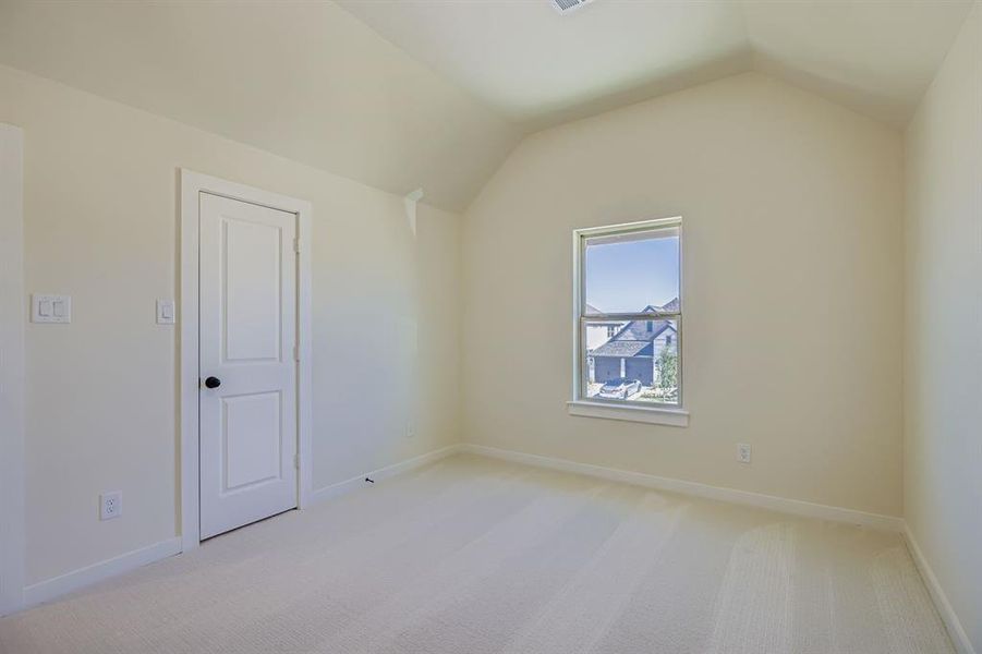 Spare room featuring light colored carpet and lofted ceiling