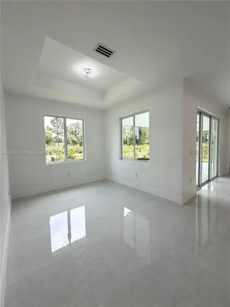 Tray ceiling featuring a modern light fixture, large-format polished tile flooring, and sliding glass doors