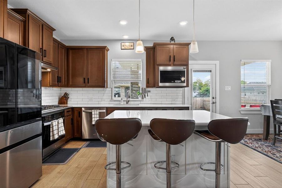 The kitchen features stainless steel appliances, a white subway tile backsplash, and wood cabinetry