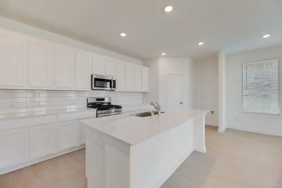 Kitchen featuring stainless steel appliances, backsplash, light wood finished floors, an island with sink, and recessed lighting