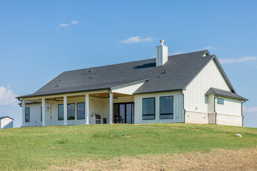 Rear view of house with a patio area, a chimney, a shingled roof, a yard, and ceiling fan