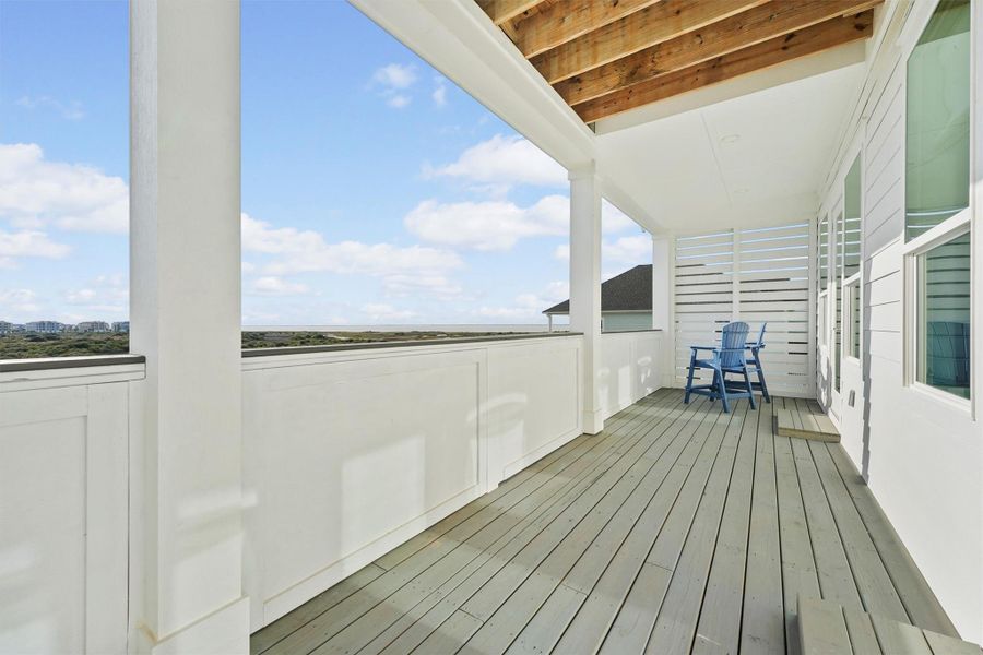 This balcony is located at the rear of the home facing the bay. It is covered and includes blue polywood chairs, perfect for relaxing and enjoying the outdoors. The space is bright and airy, ideal for leisure or entertaining.