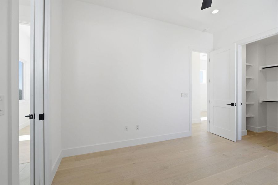 Unfurnished bedroom featuring light wood finished floors, a walk in closet, recessed lighting, and a ceiling fan
