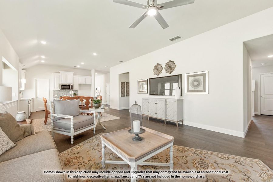 Open-concept living room with vaulted ceiling, ceiling fan, hardwood floors, and view into kitchen and dining area. Open-concept living room with vaulted ceiling, ceiling fan, hardwood floors, and view into kitchen and dining area.