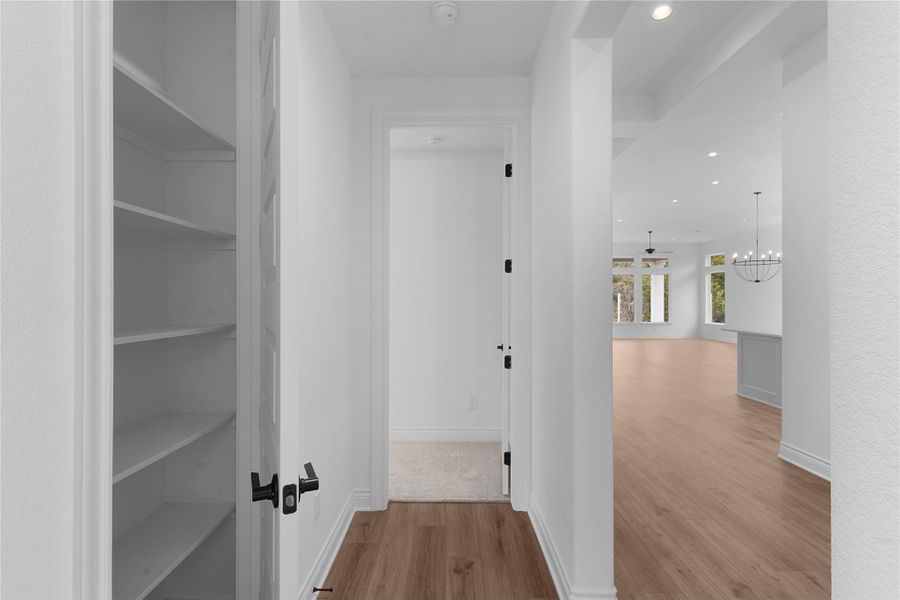 Hall with light wood-style floors and a chandelier