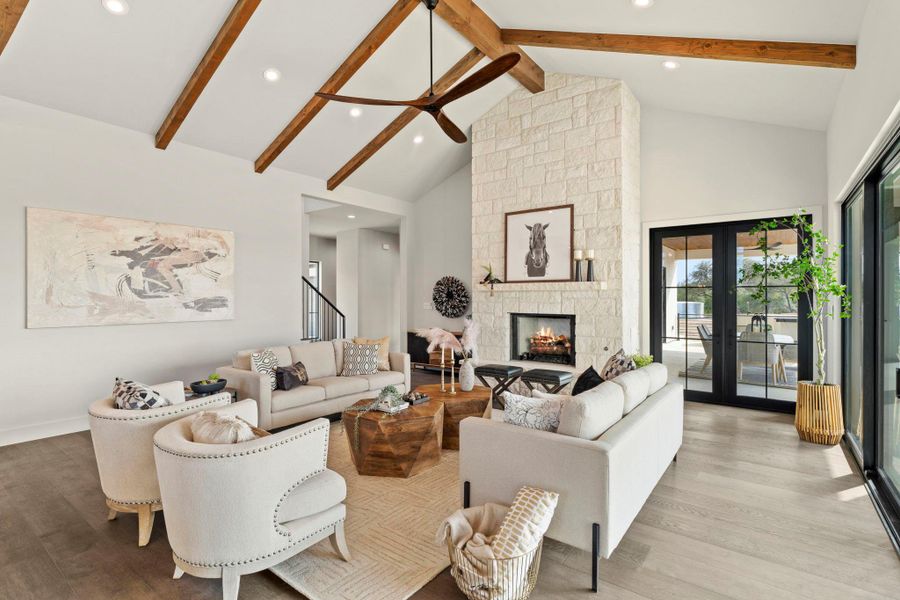 Living room with a fireplace, french doors, wood finished floors and stylish fan.