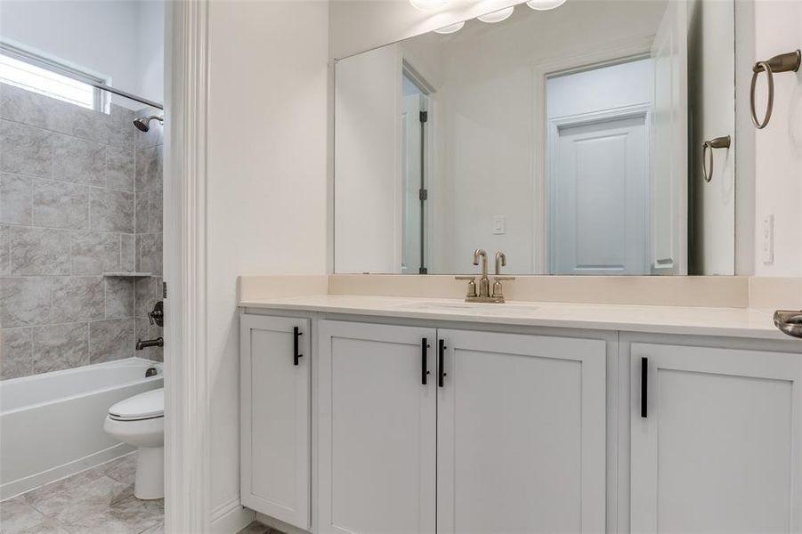 Full bathroom with tiled shower / bath, and toilet with door separating from sink, vanity area