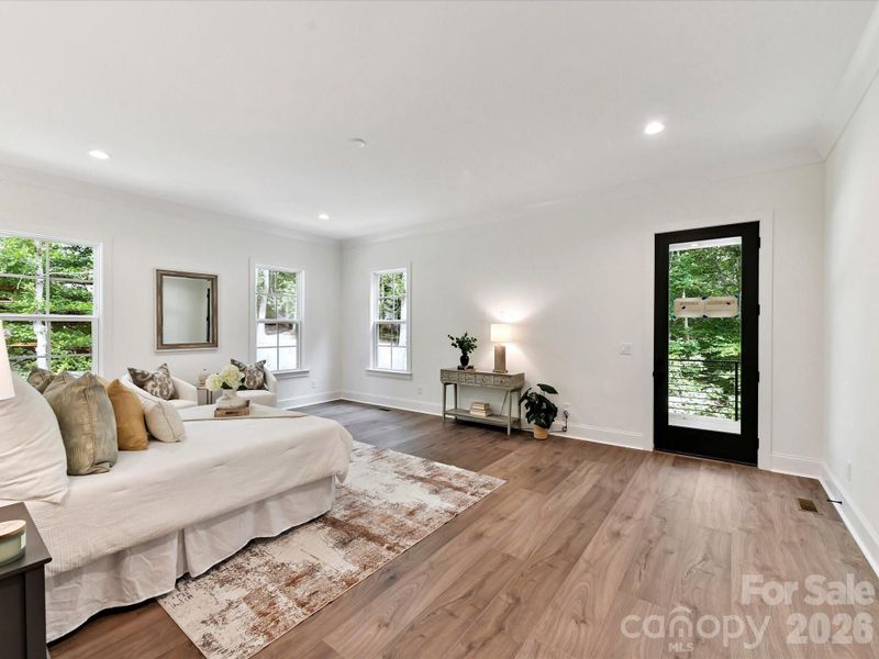 Spacious primary suite featuring a serene sitting area, large windows with wooded views, and plenty of room to relax and unwind.
