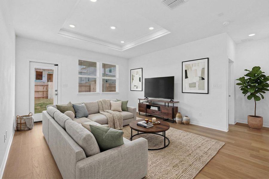 Living room featuring recessed lighting, light wood-type flooring, and a tray ceiling