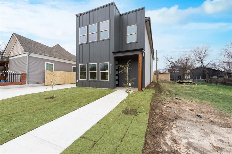 Contemporary home with fence, board and batten siding, and a front yard