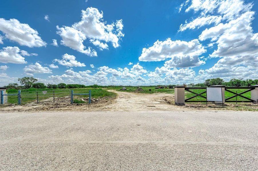 Front view of the gated entrance showing road access, entry drive, and approach into the private acreage subdivision.