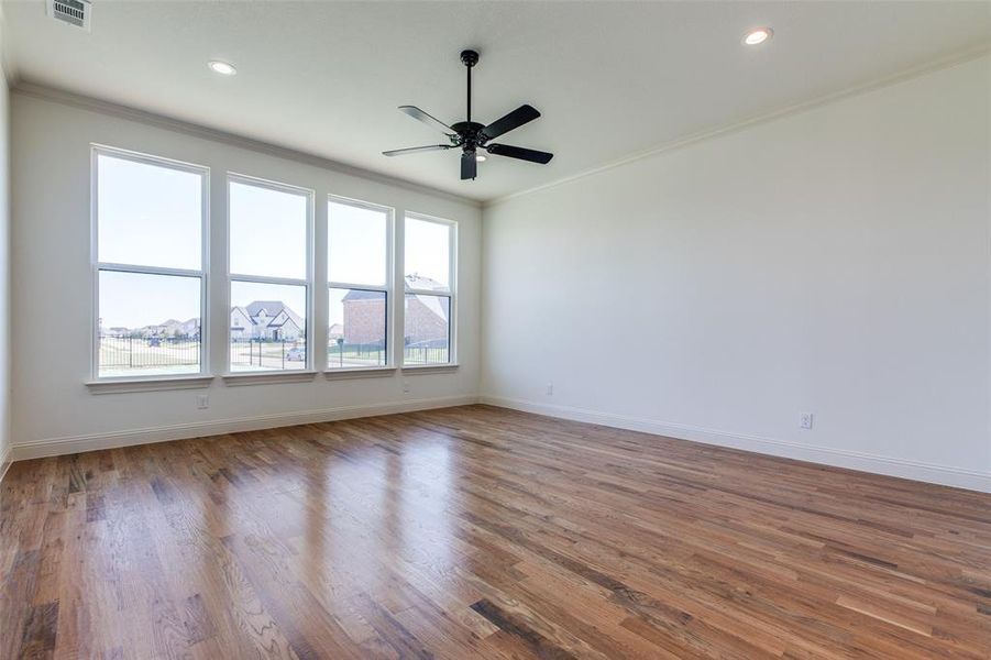 Spare room featuring ceiling fan, crown molding, and wood-type flooring