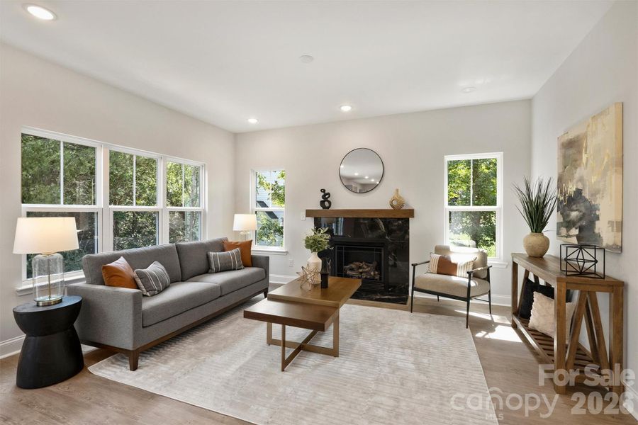 Open concept living room featuring large windows, gas fireplace, and an open floor plan that adjoins the kitchen.