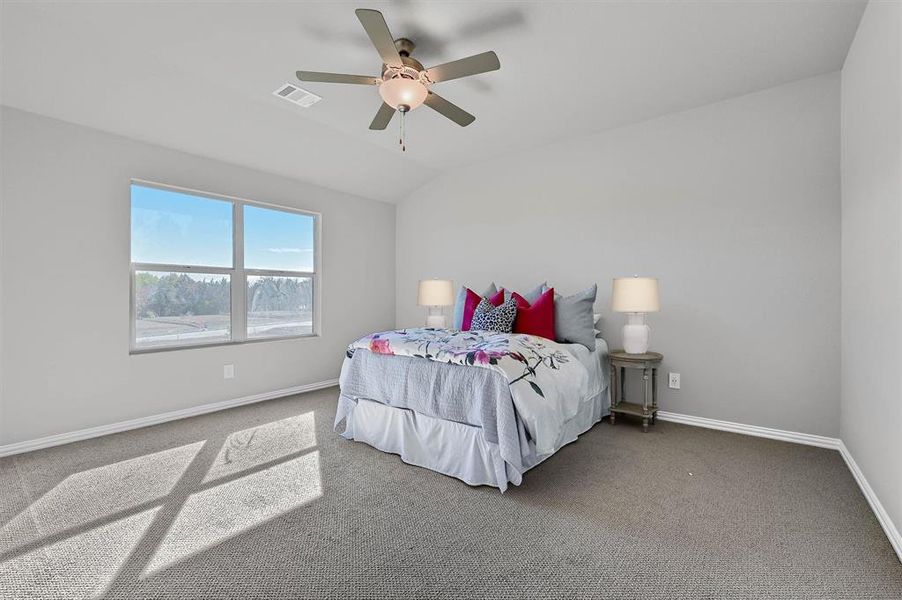 Carpeted bedroom featuring ceiling fan and lofted ceiling