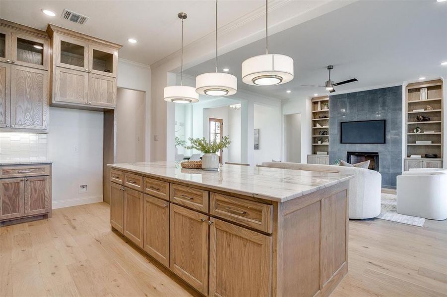 Kitchen featuring Quartzite countertops, tasteful backsplash, light hardwood / wood-style flooring, a kitchen island, and appliances with stainless steel finishes