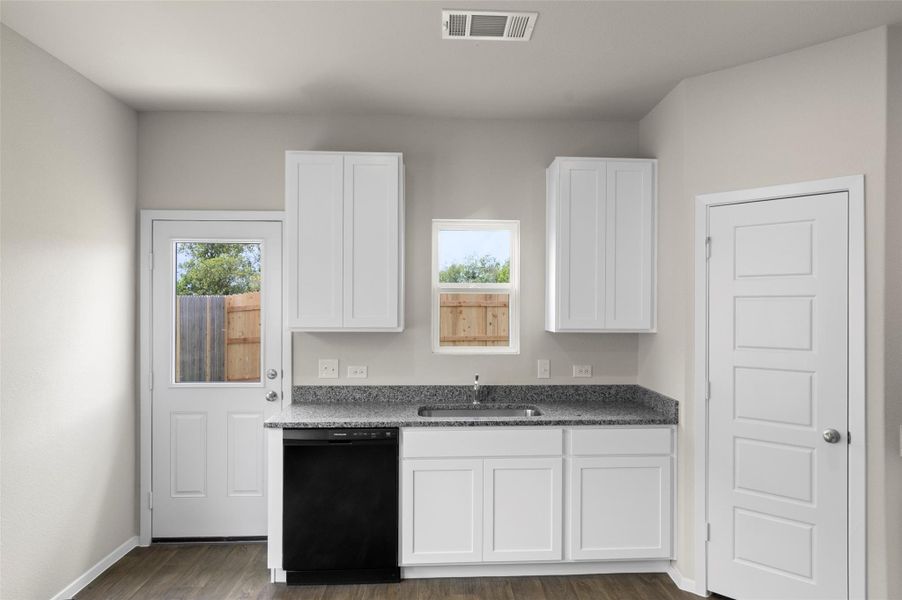 Kitchen featuring black dishwasher, plenty of natural light, and white cabinetry Kitchen featuring black dishwasher, plenty of natural light, and white cabinetry